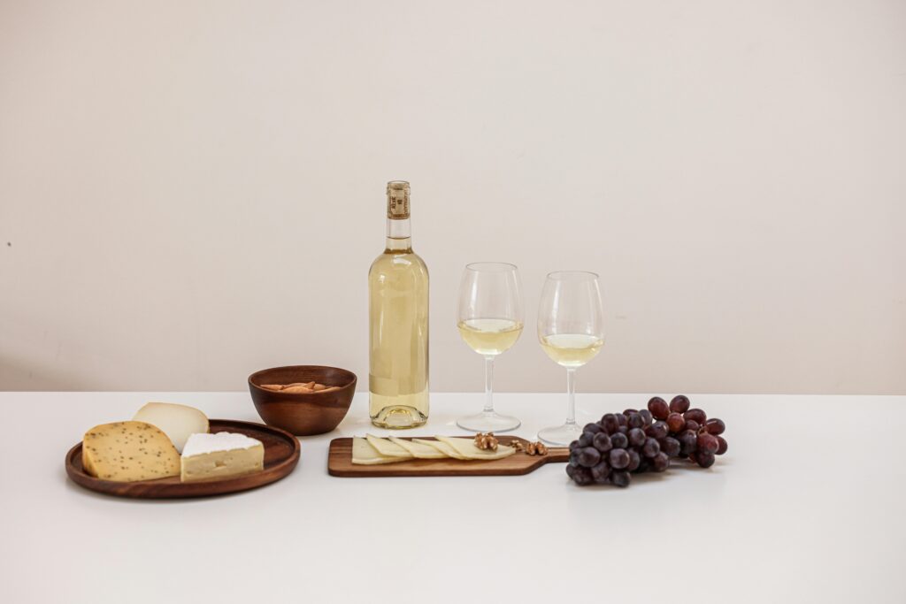 A stylish arrangement of cheese, wine, grapes, and nuts on a minimalist table setting.